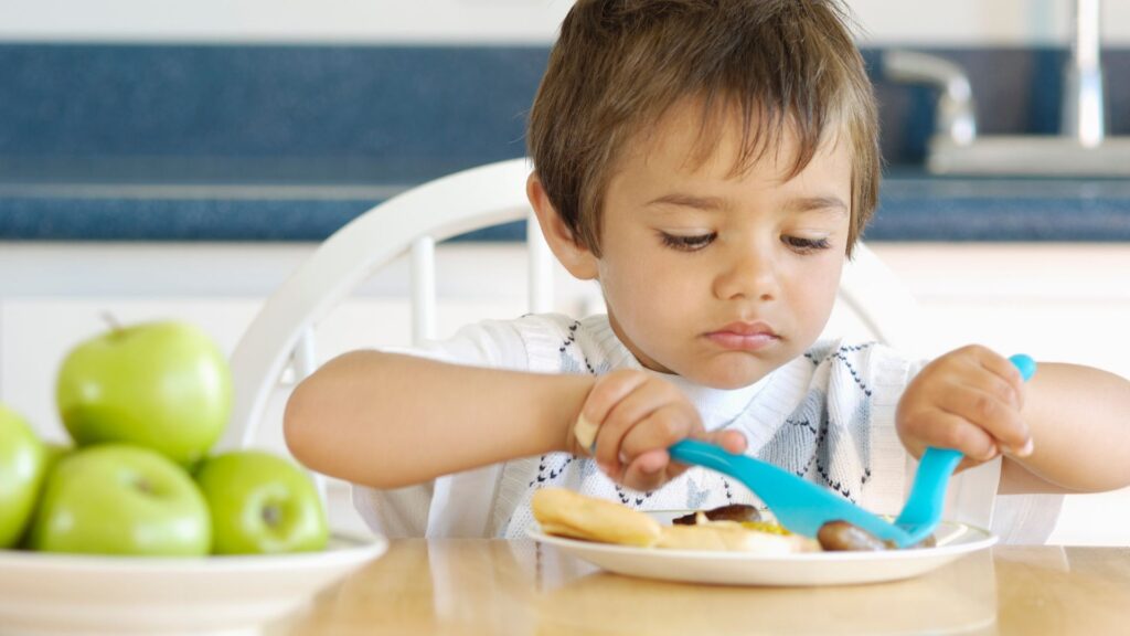 Bambino che assaggia una piatto di carne