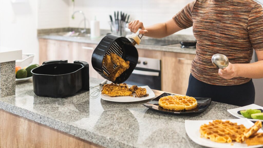 Una donna che cucina diversi pasti con la friggitrice ad aria